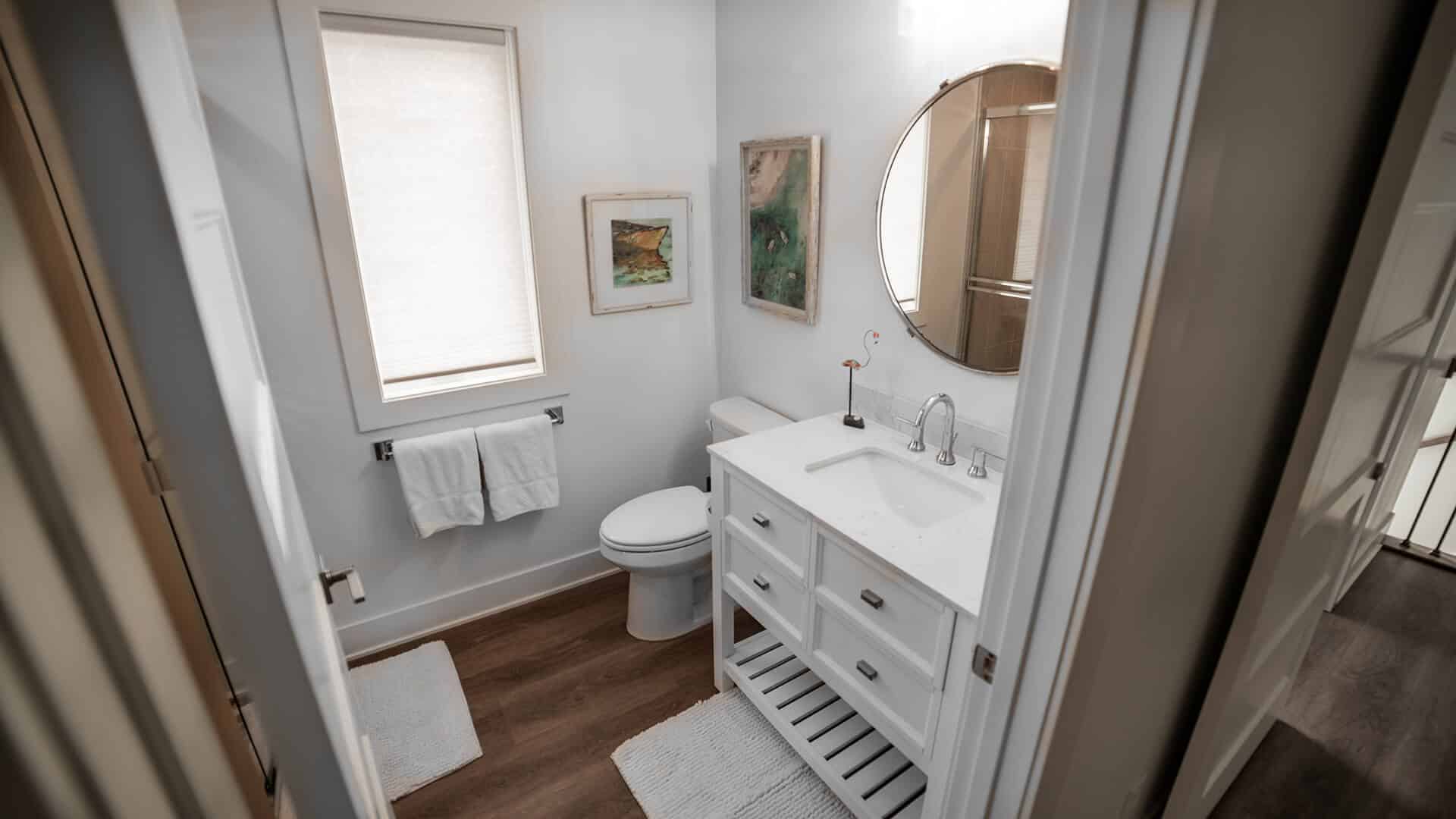 Bathroom with white vanity, round mirror, and natural light.