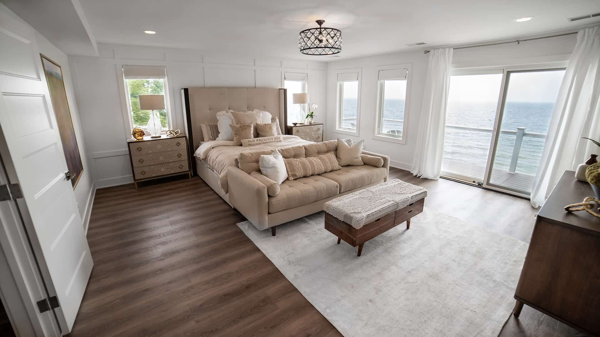 Bright living room with large windows overlooking the ocean, stylish furniture, and hardwood floors.