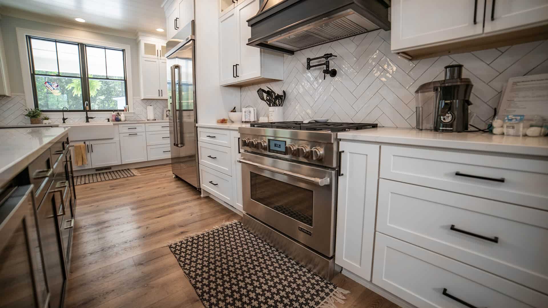 Bright and spacious kitchen featuring white cabinets, stainless steel stove, and large window for na.
