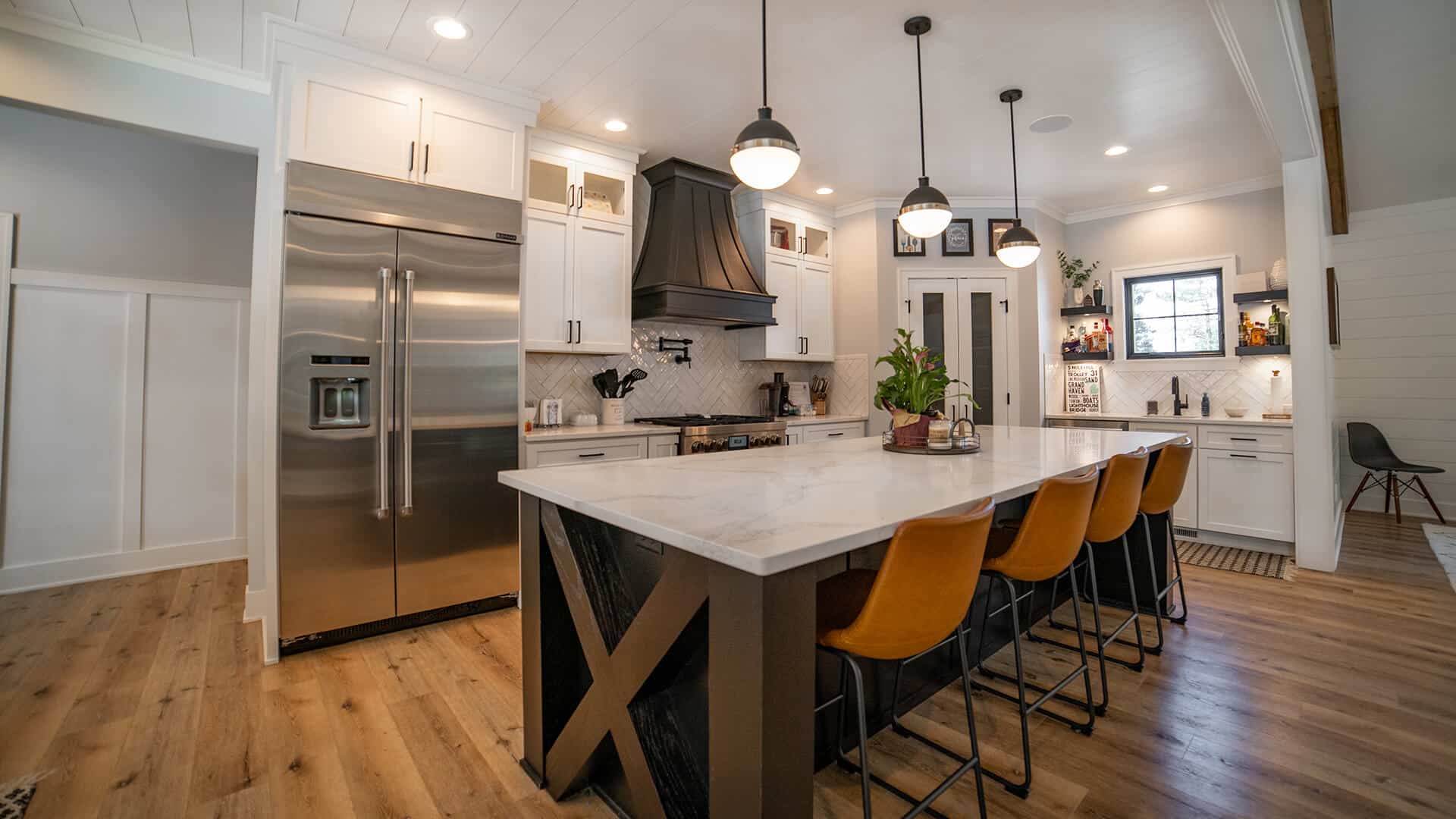 Contemporary kitchen featuring a large island, stainless steel refrigerator, and modern lighting fix.