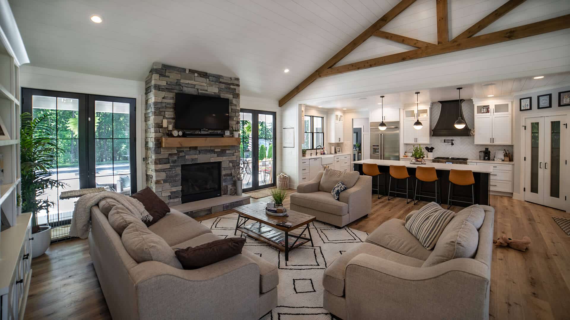 Bright and spacious living room with a stone fireplace and large windows, perfect for family gatheri.