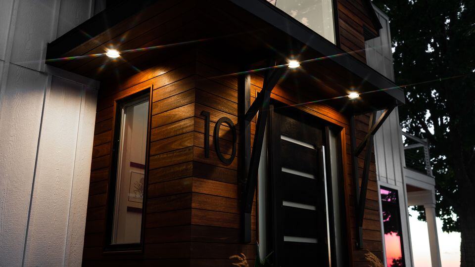 Modern wooden house exterior with illuminated entryway and contemporary design.