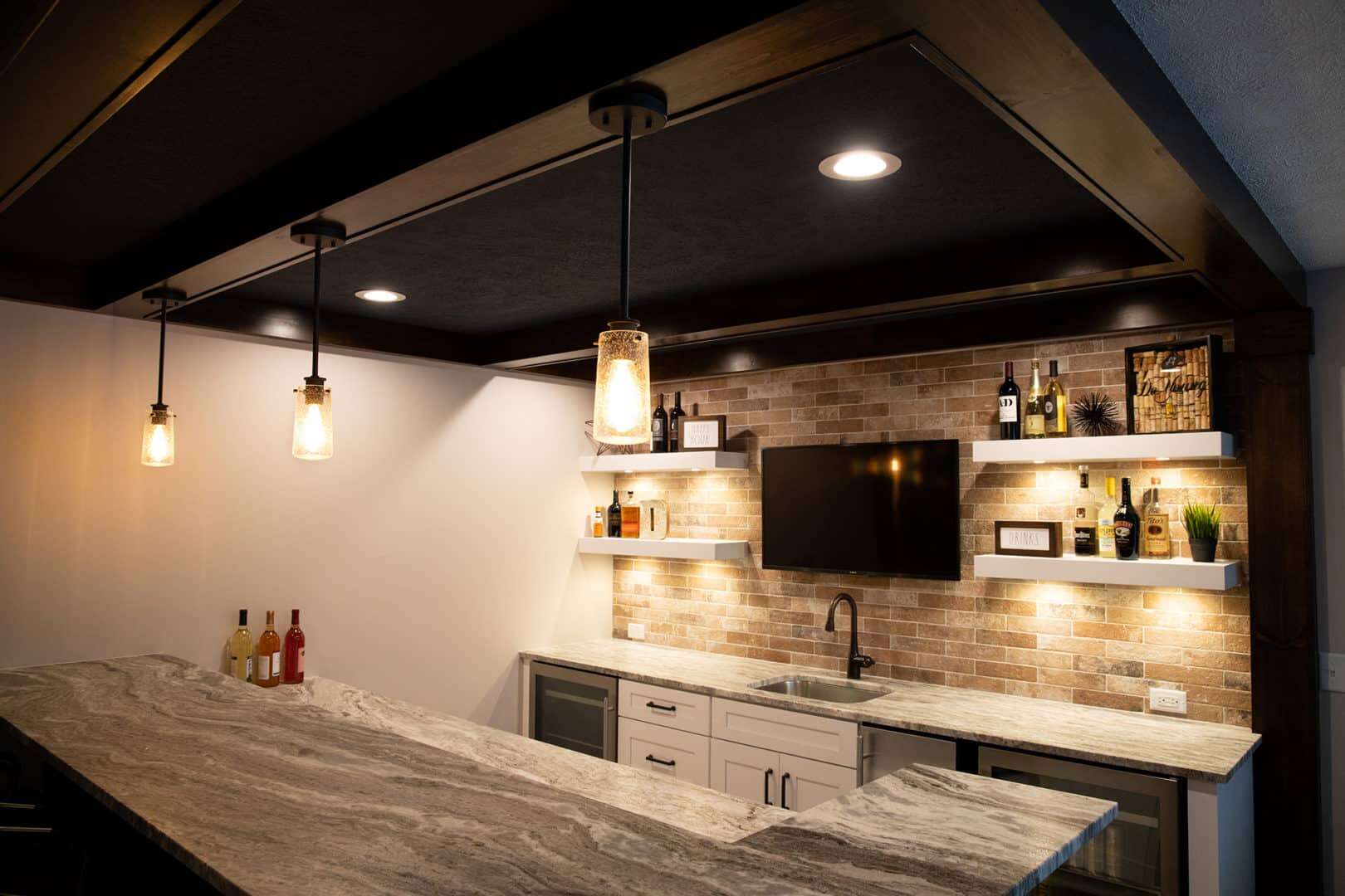 Basement bar featuring a brick accent wall, ambient pendant lighting, and a sleek countertop for ent.