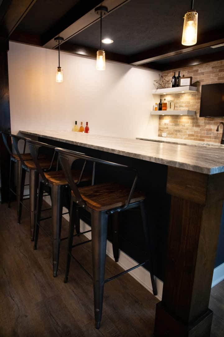 Modern kitchen bar with pendant lights, wooden stools, and contemporary decor.