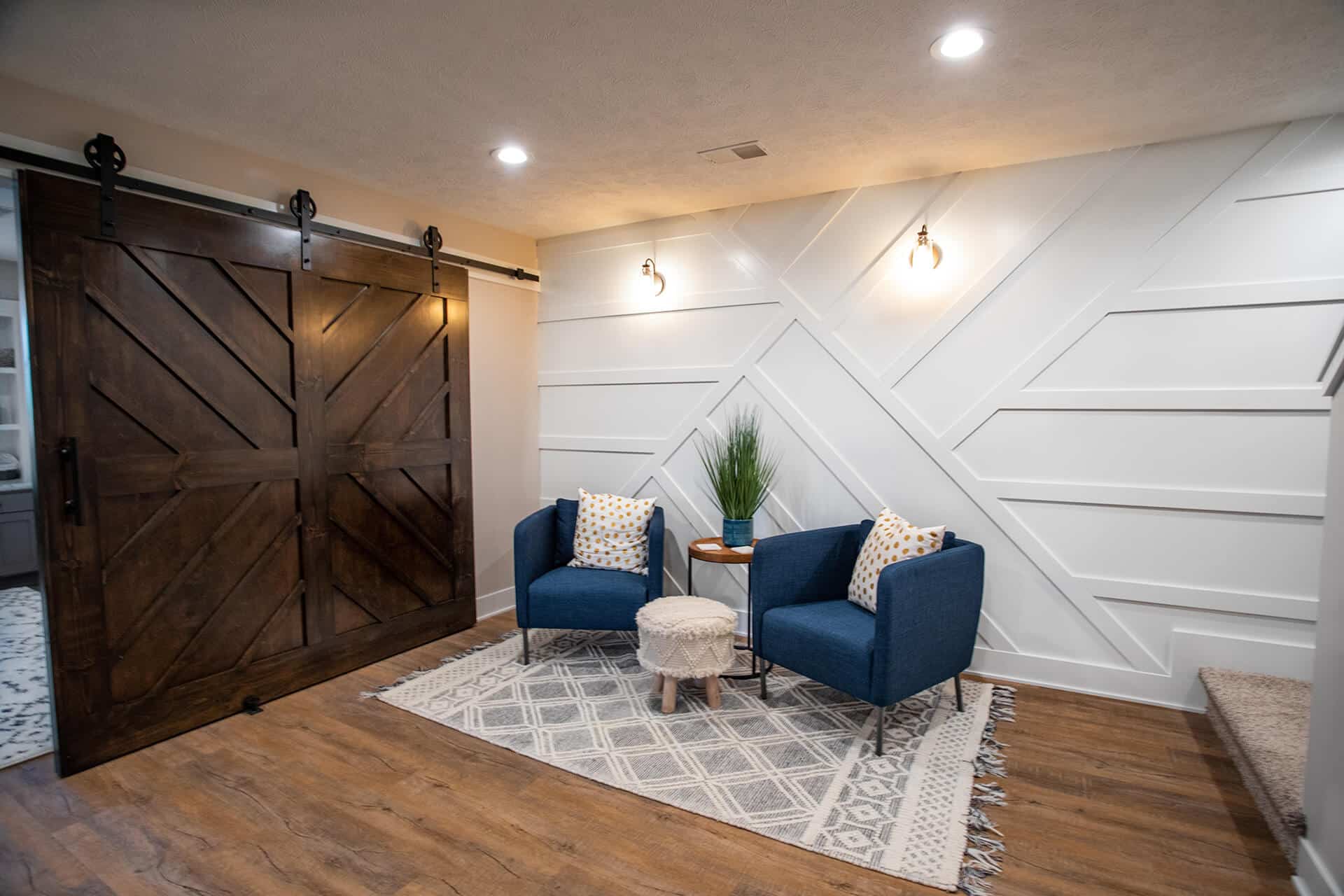 Modern living room with stylish blue chairs and decorative wall design.