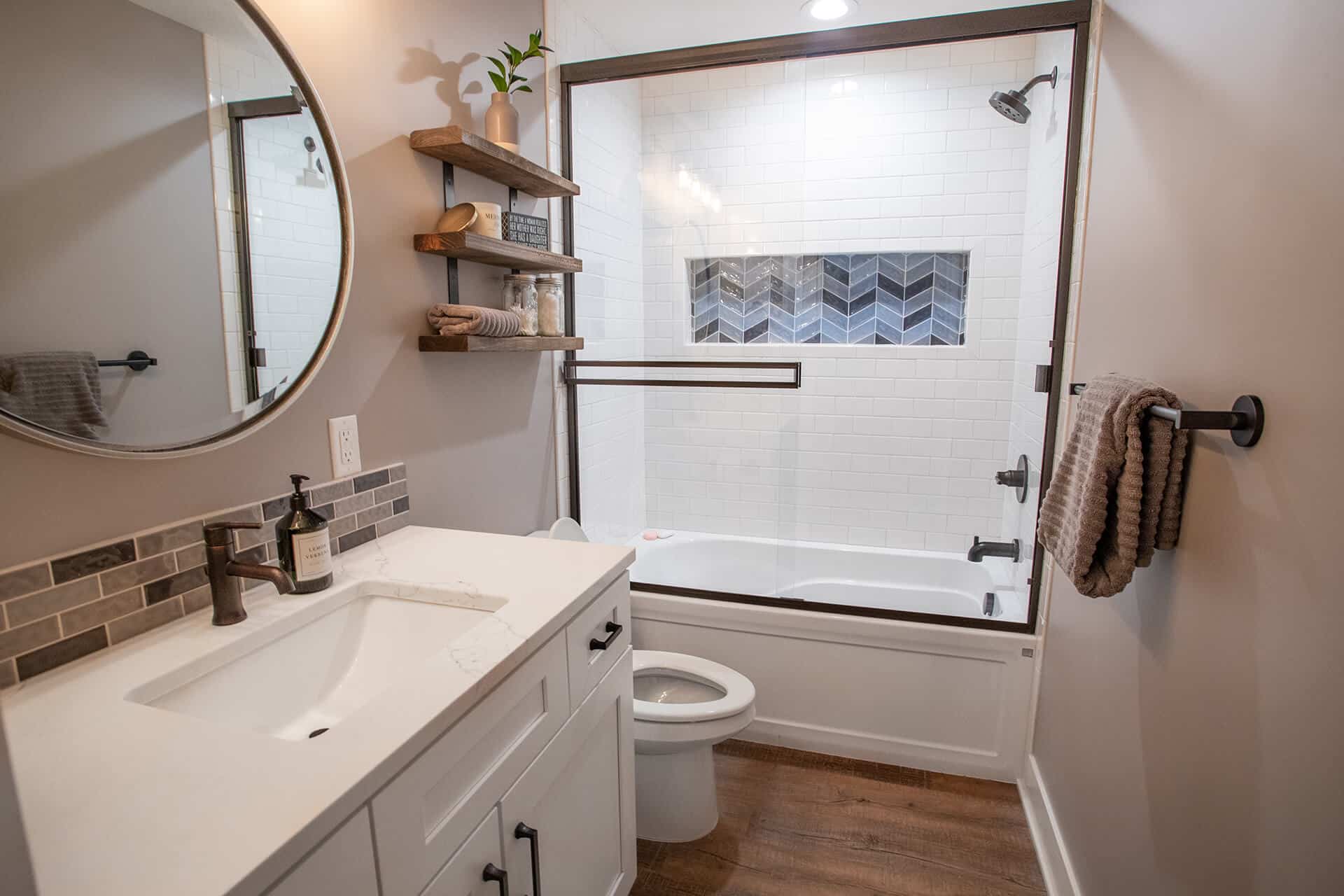 Bathroom with glass-enclosed shower, white tiles, and wooden accents.
