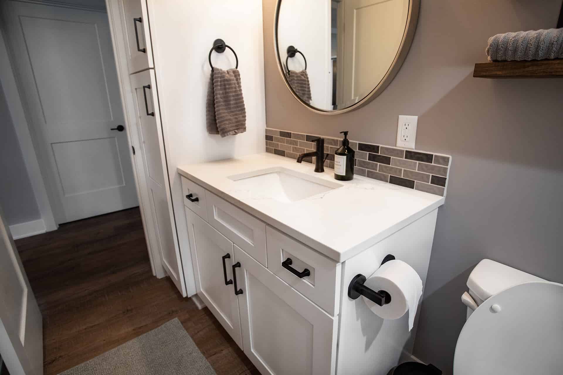 Modern bathroom vanity with white cabinetry and black fixtures.