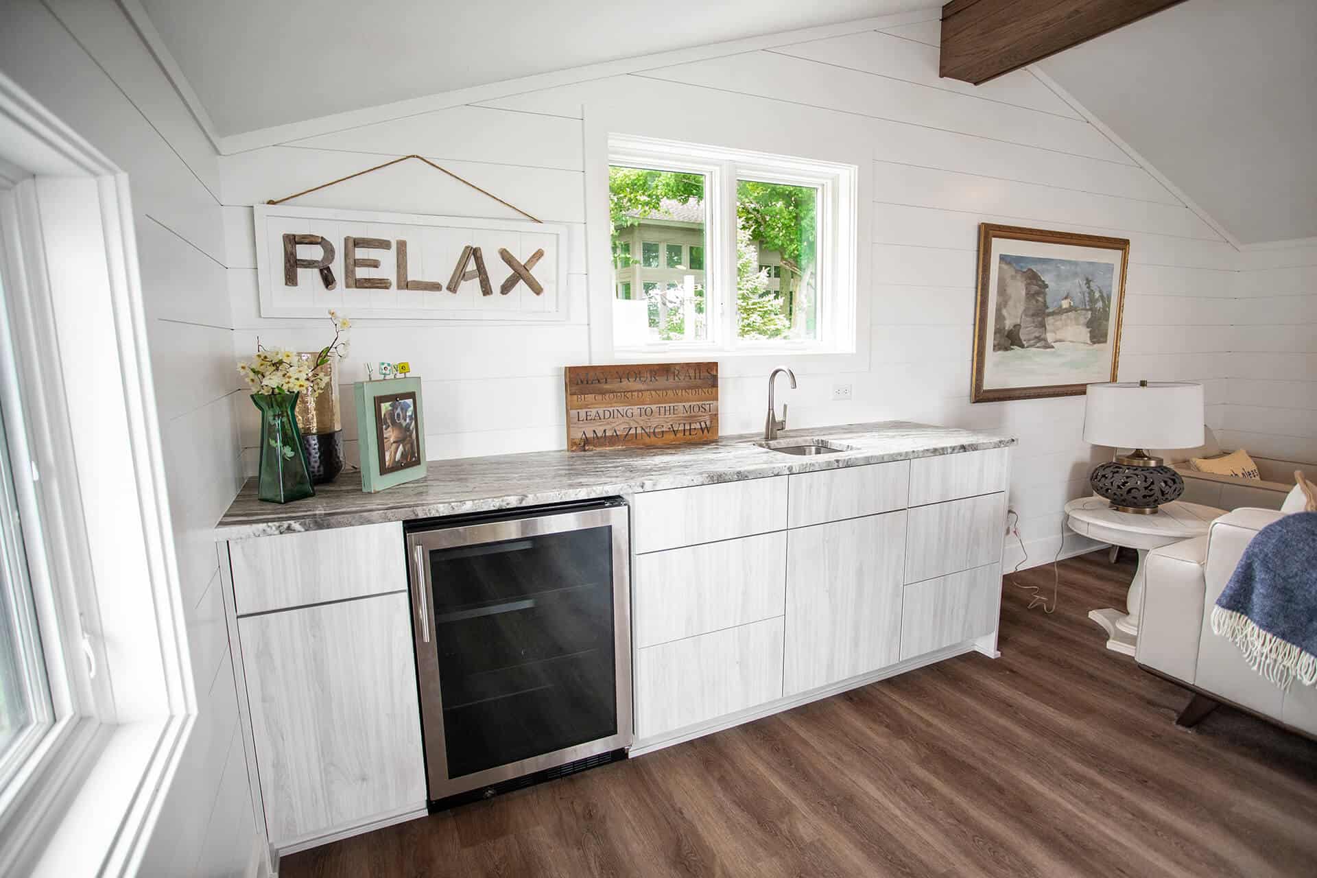 Modern kitchen with white cabinetry, small fridge, and relaxing decor.