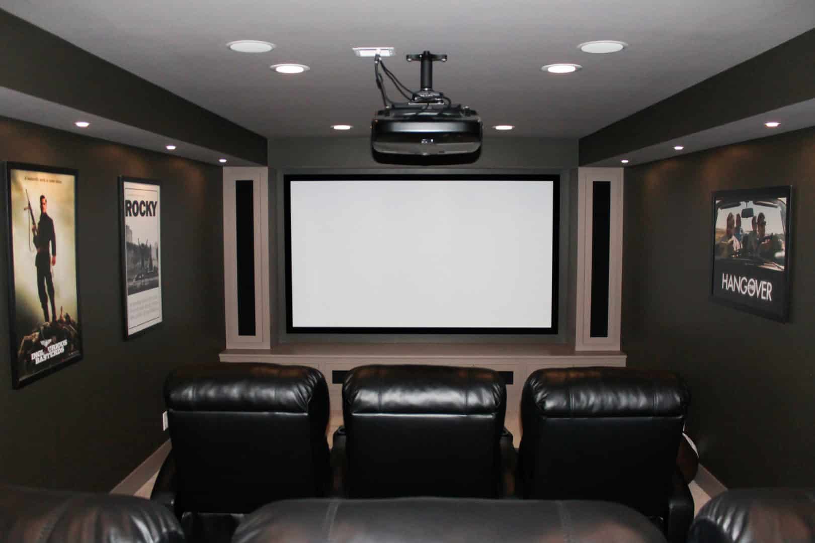 Home theater room with large screen and comfortable leather seating.