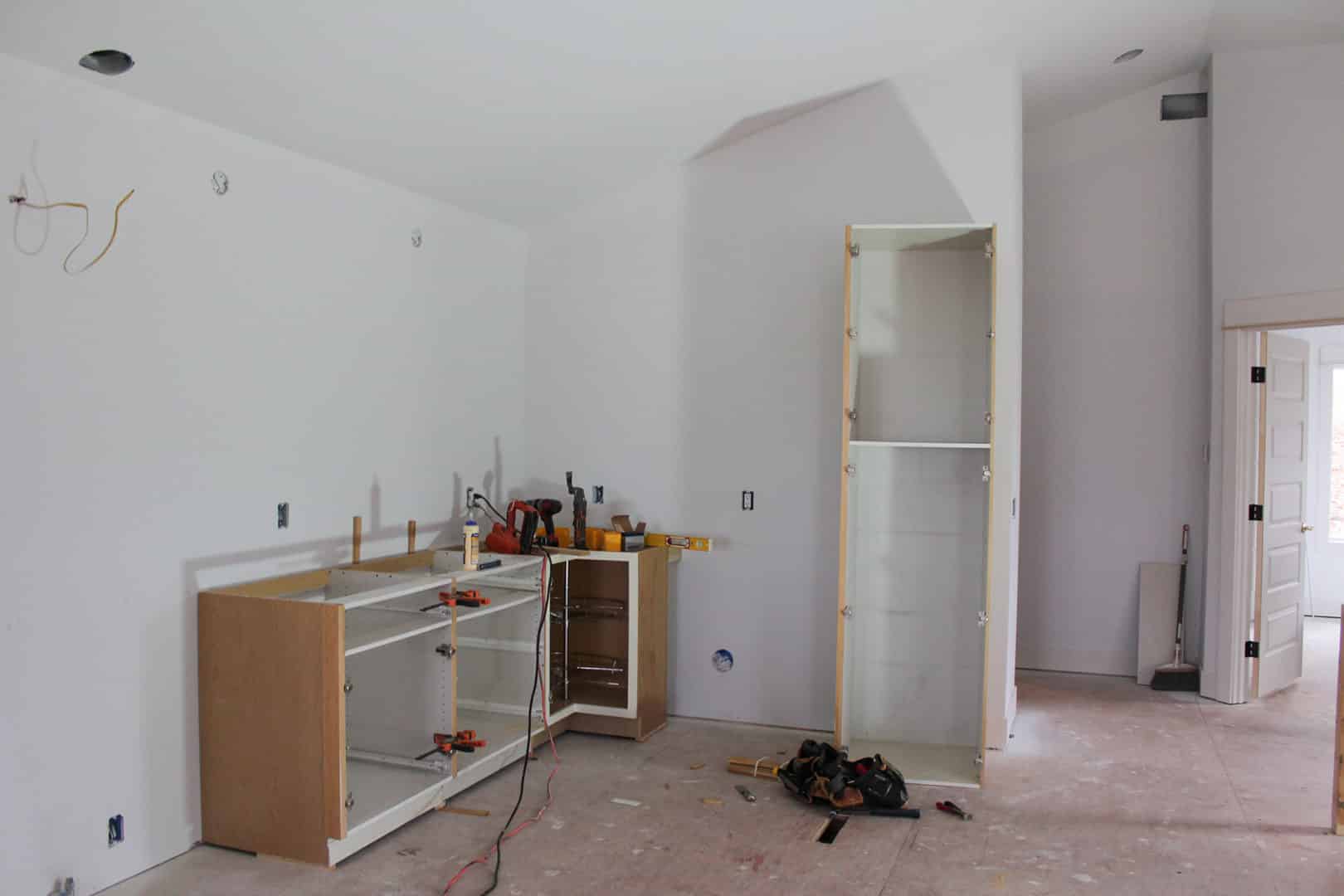 Modern kitchen under construction with cabinetry and tools in progress.