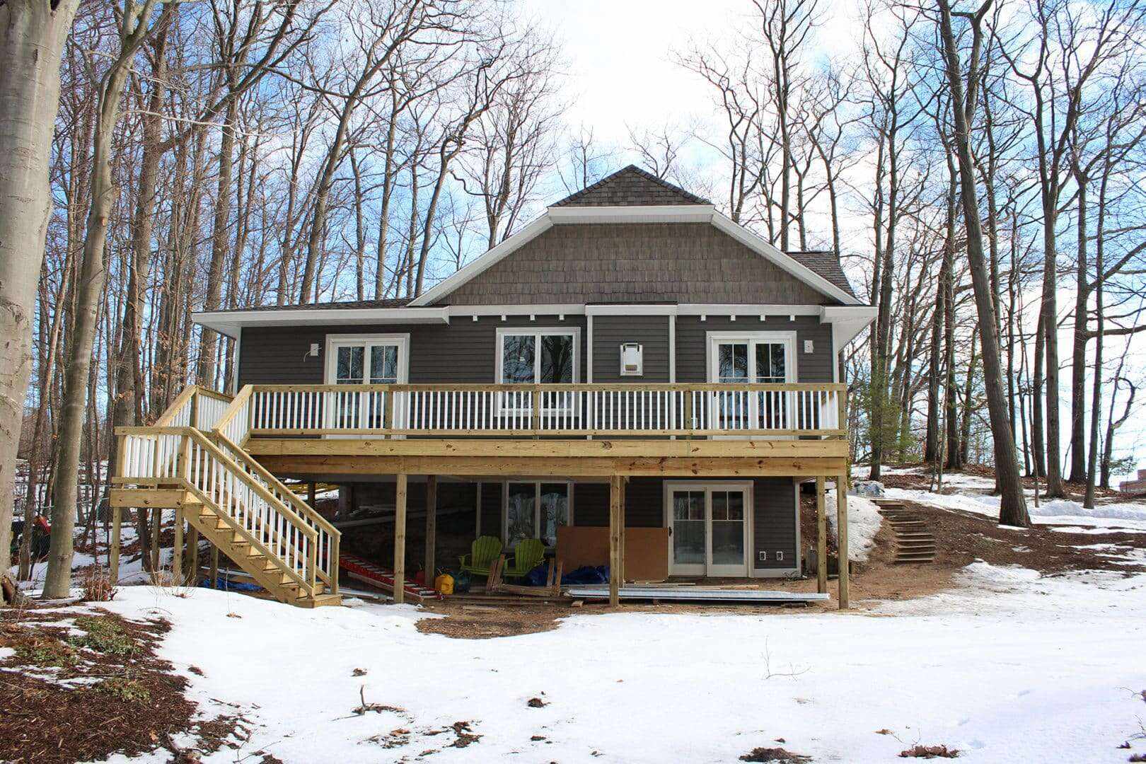 Modern forest home with spacious deck and large windows in a wooded area.