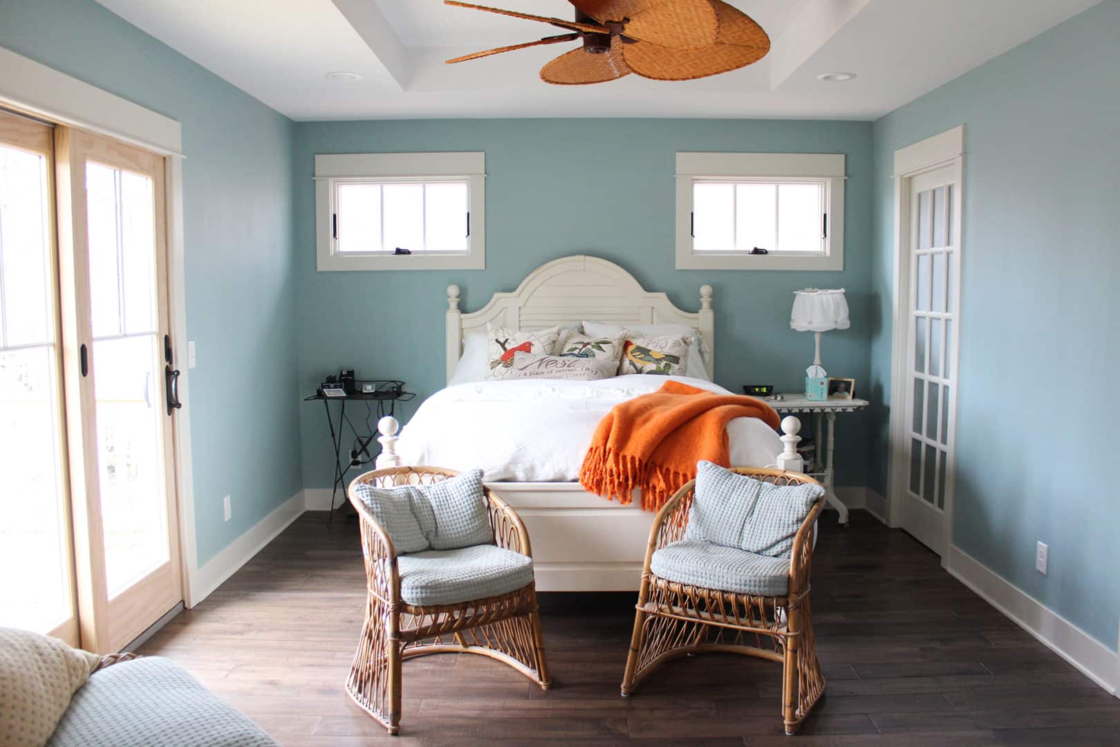 Bright bedroom with ocean views, wicker chairs, and coastal decor.