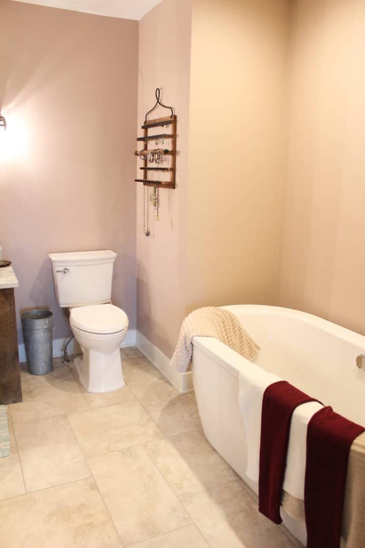 Bathroom with a classic white bathtub and toilet, featuring warm beige walls and decorative accessor.