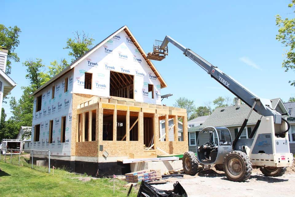New residential home under construction with crane and framing in progress.