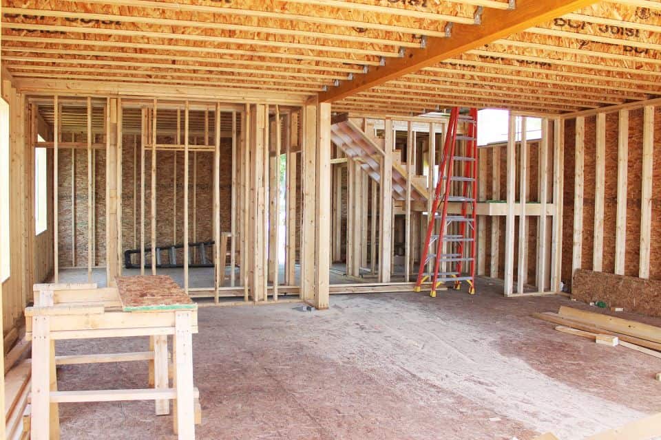 Interior framing of a new house under construction with wooden studs and beams.