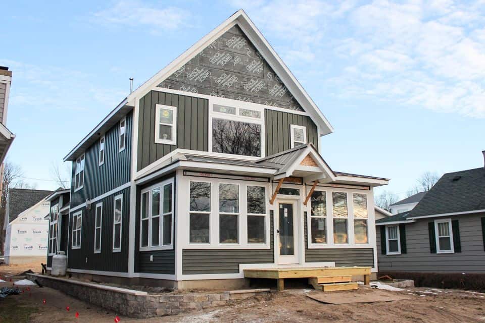 New Craftsman-style house with black siding and large windows in progress.