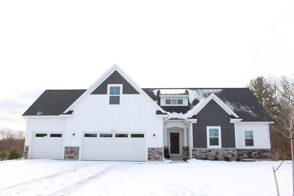 Modern white and gray house with a spacious garage and snow-covered yard.