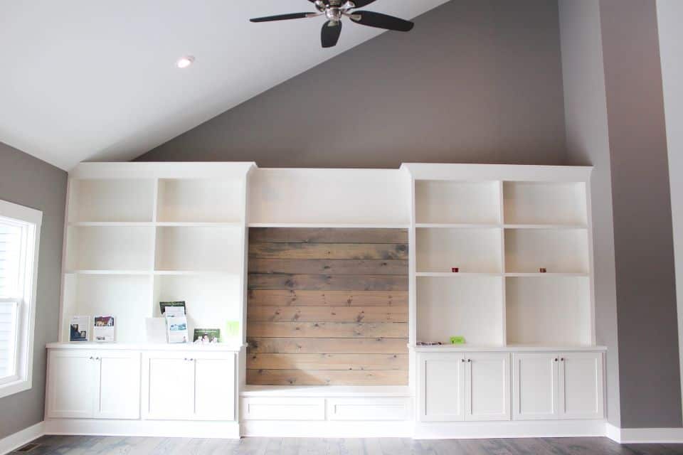 Living room wall with white built-in shelves and a central wood accent panel, ideal for home enterta.
