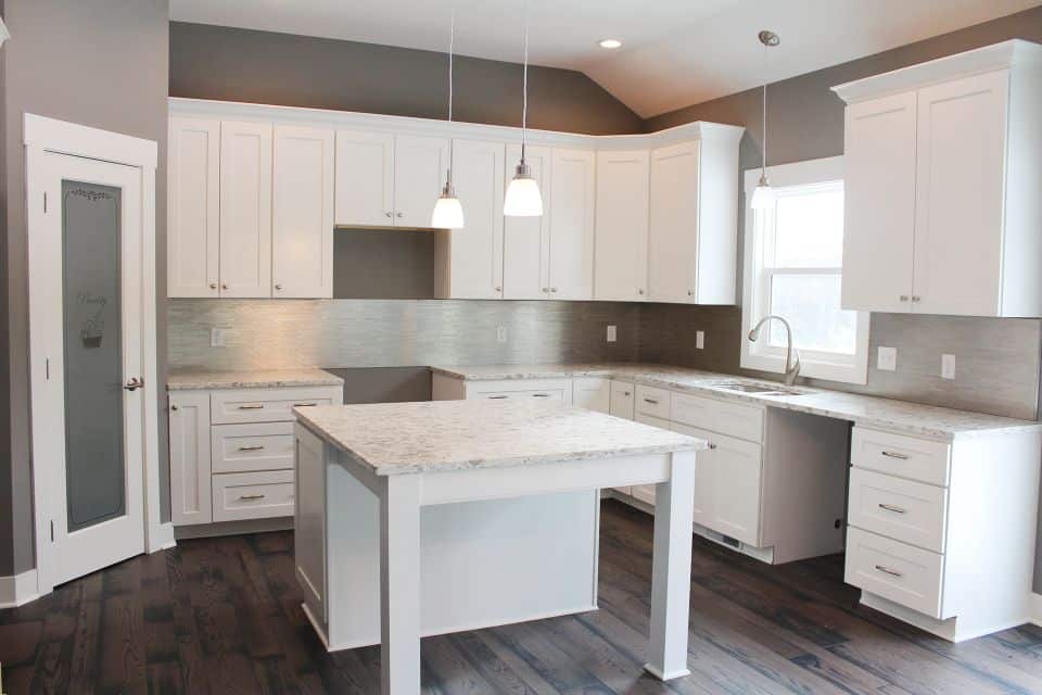 White kitchen with island, cabinetry, and stainless steel appliances.
