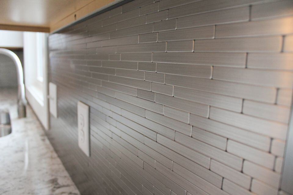 Gray tile kitchen backsplash with modern design and natural lighting.