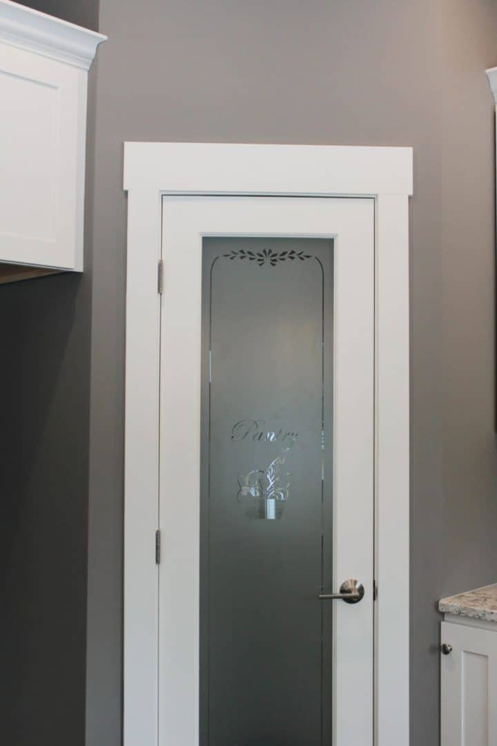 Modern white interior door with frosted glass panel and decorative etching.