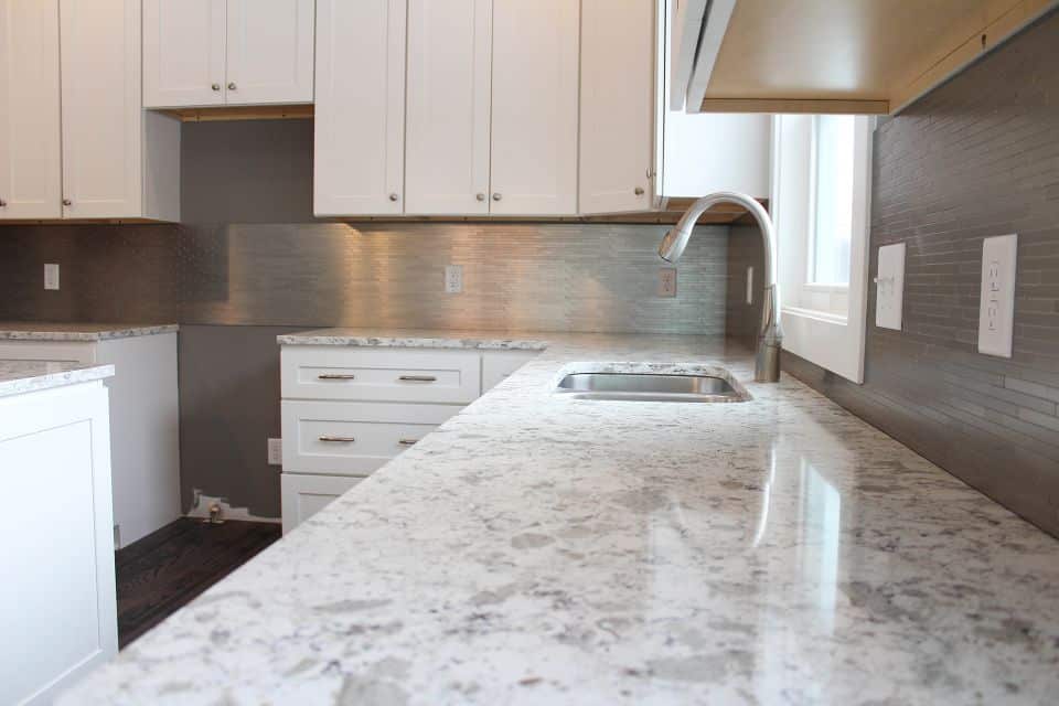 Modern kitchen with granite countertops and white cabinetry.