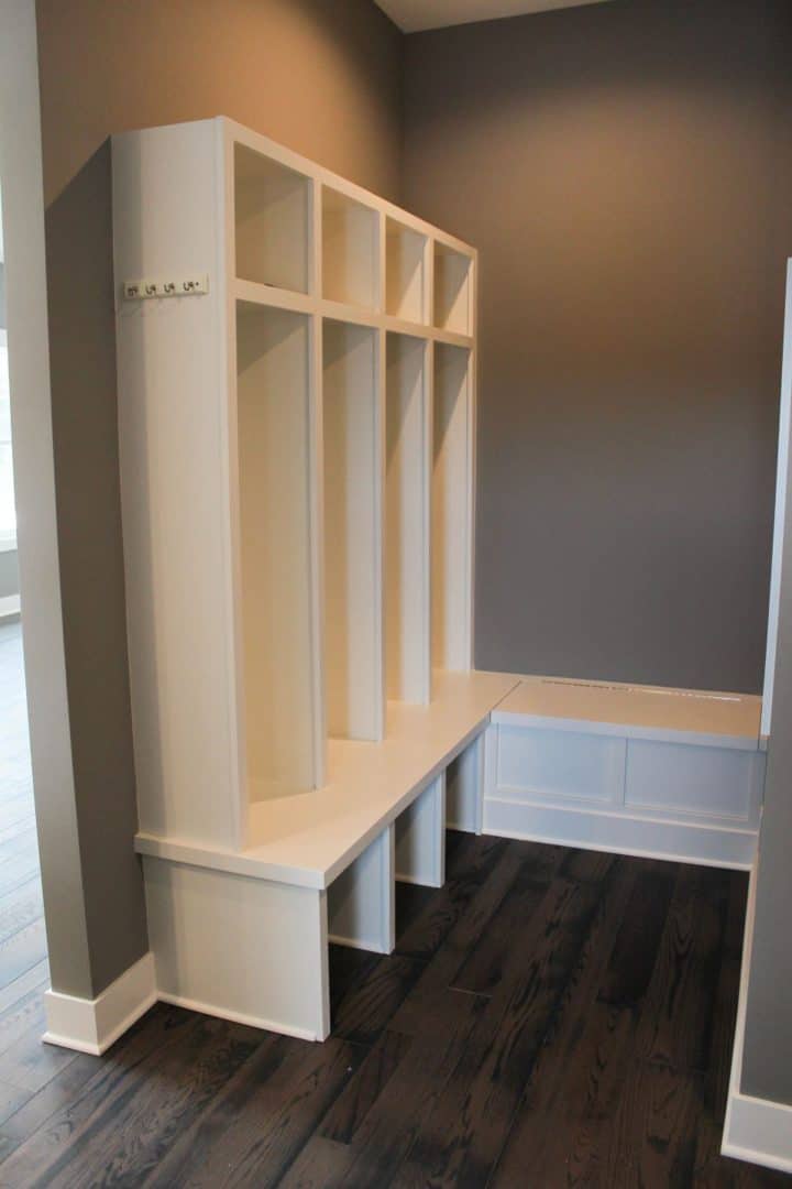 Modern white mudroom bench with cubbies and hooks for organization.