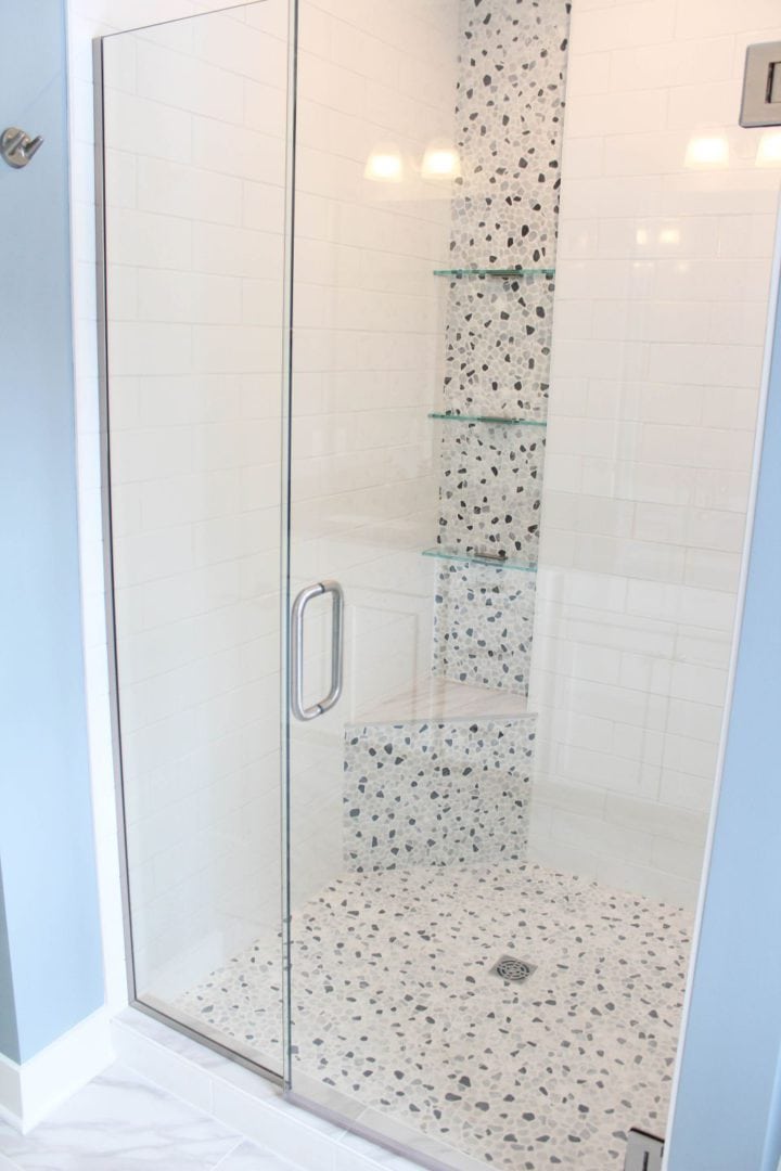 Modern glass shower with pebble tile accents and built-in shelves for a sleek bathroom upgrade.