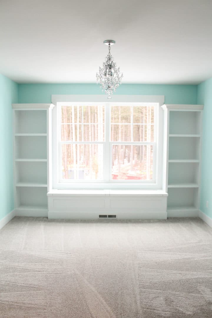 Living room with large window, built-in shelves, and chandelier in Livingston Homes property.