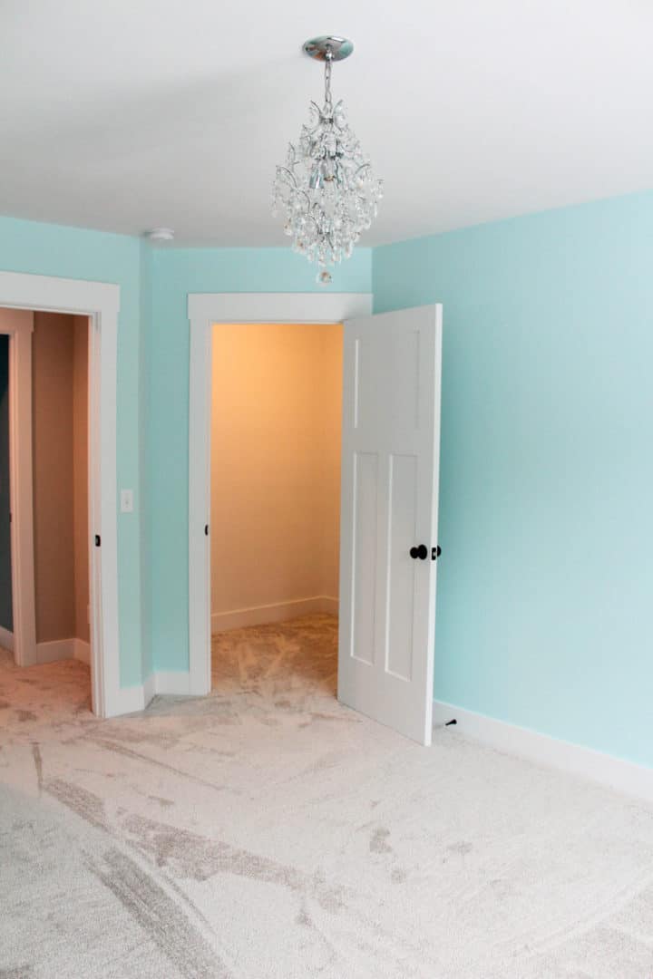 Bright bedroom with light blue walls and elegant chandelier lighting.