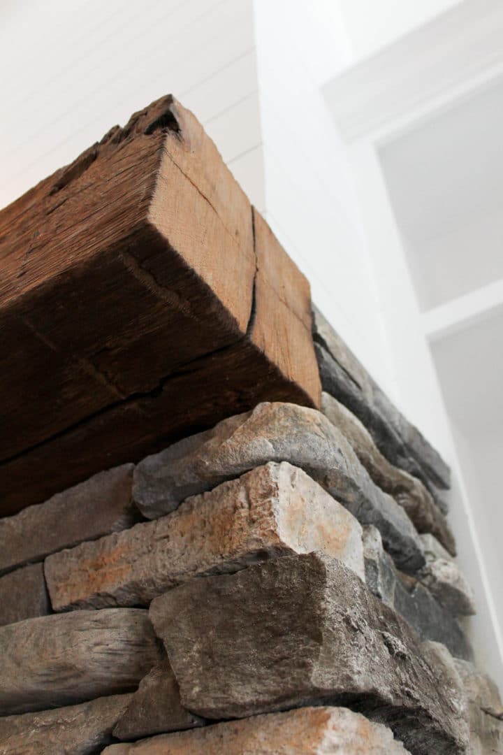 Rustic stone and wood fireplace mantel in living room.