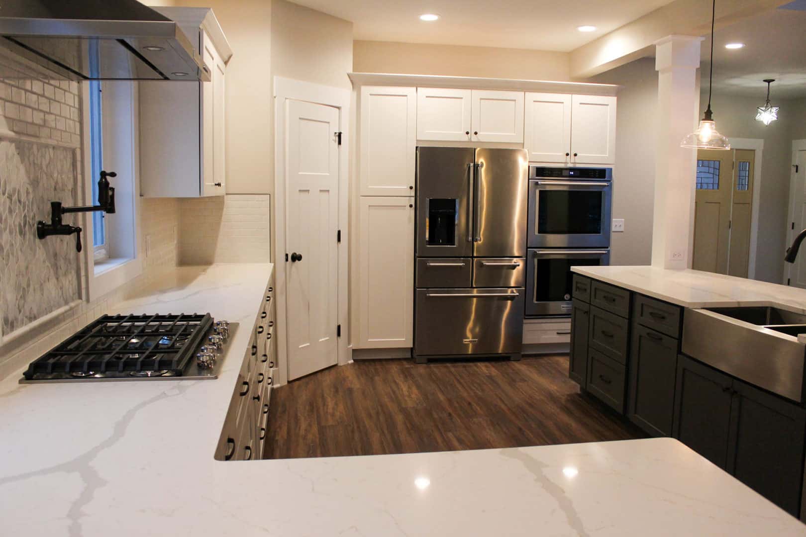 Spacious kitchen featuring stainless steel refrigerator, oven, and gas stove with white cabinets and.