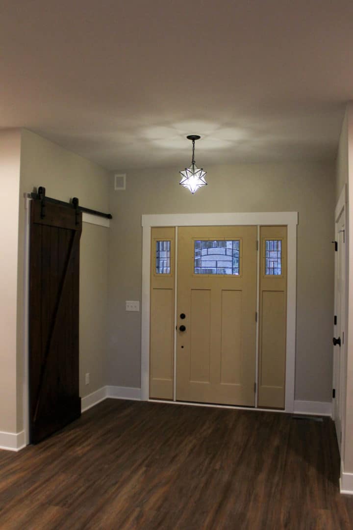 Entryway with stylish wooden door featuring decorative glass panels and modern lighting fixture.