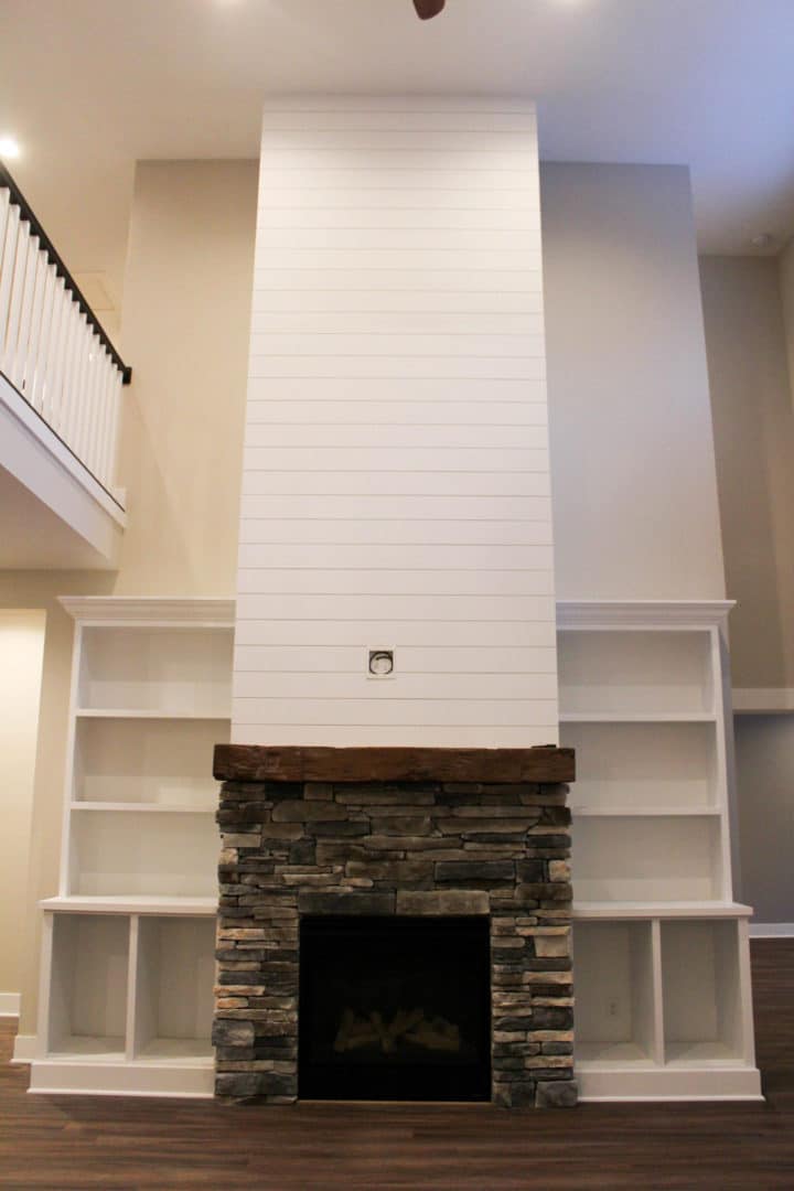 Modern living room fireplace with built-in white shelves and stone accents for cozy home decor.