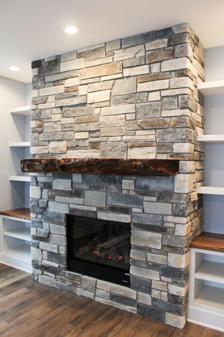 Elegant stone fireplace with wooden mantel in living room.