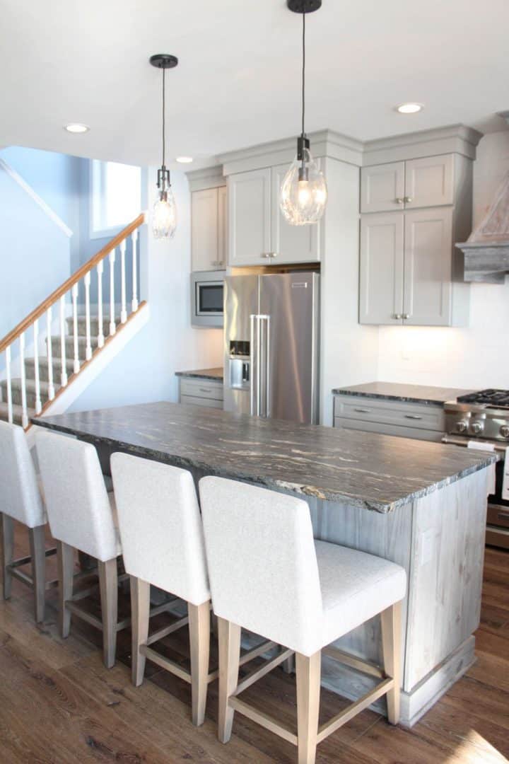 Bright, modern kitchen featuring a large island, white cabinetry, stainless steel appliances, and st.
