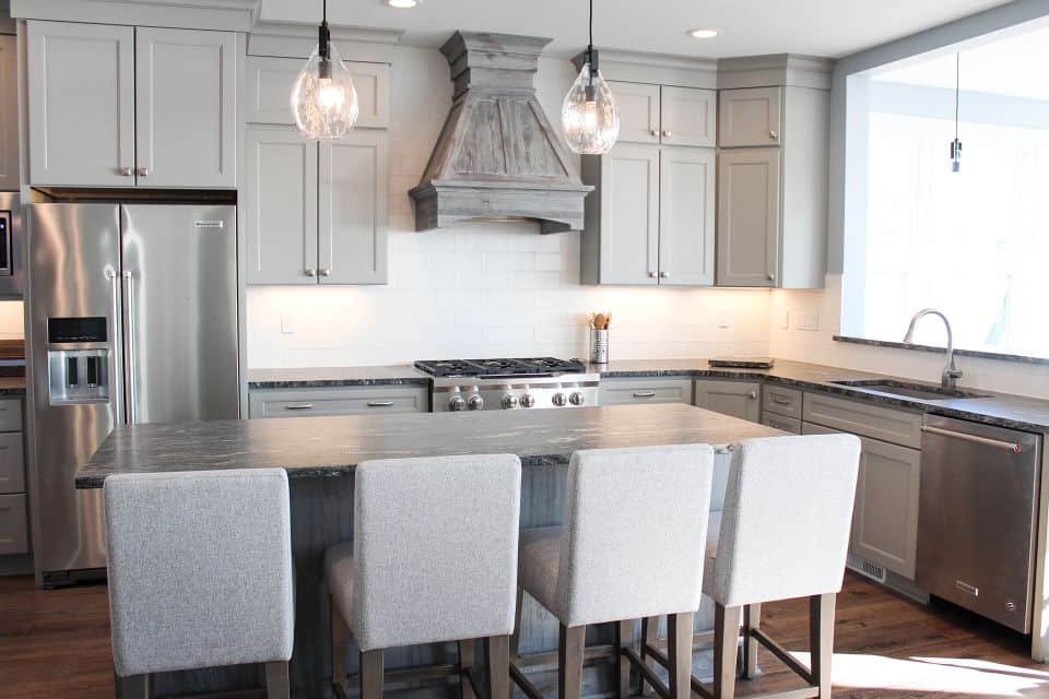 Modern kitchen with gray cabinets, stainless steel refrigerator, and island with seating.