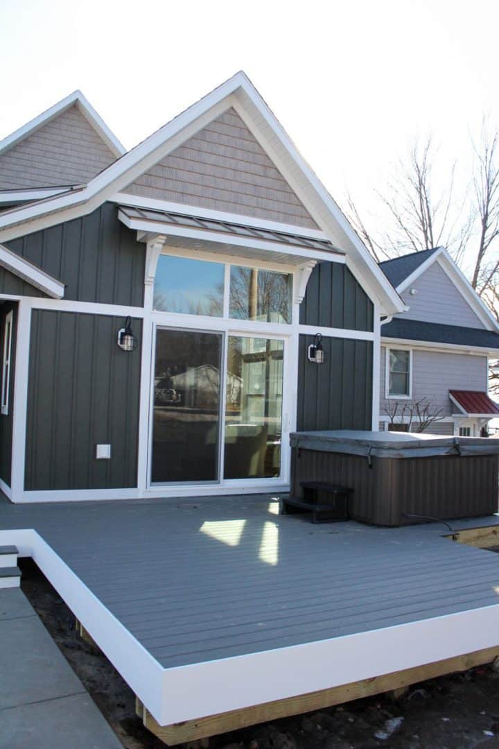 Modern gray house with large glass doors and outdoor deck.
