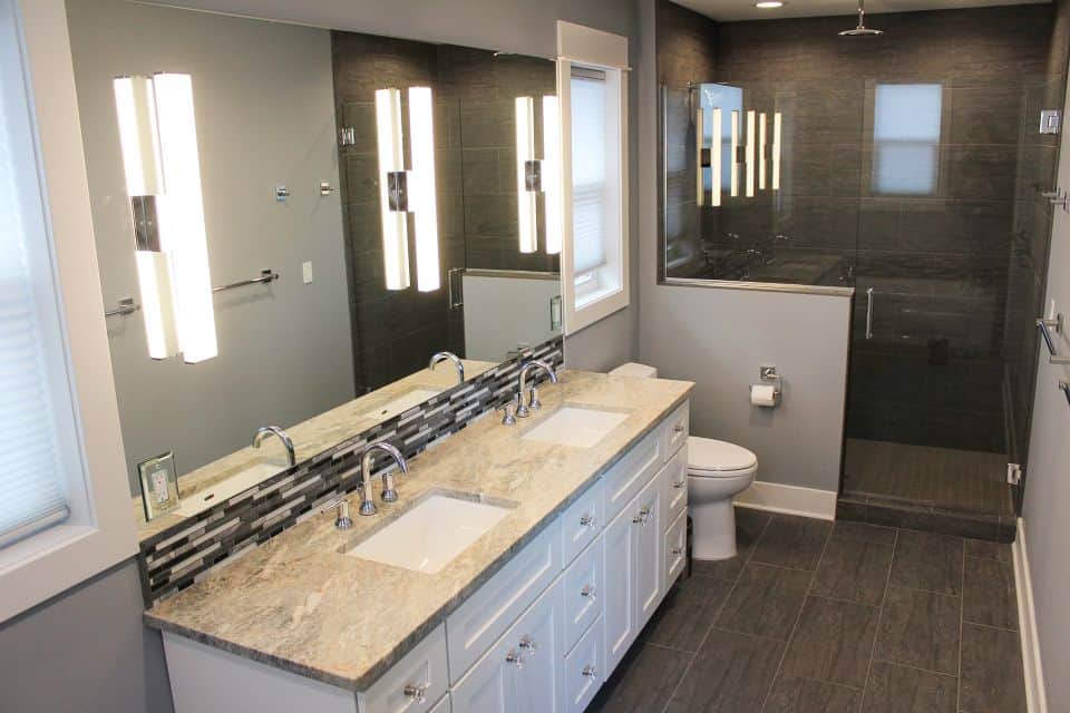 Modern bathroom featuring dual sinks, large mirror, and walk-in shower by Livingston Homes.