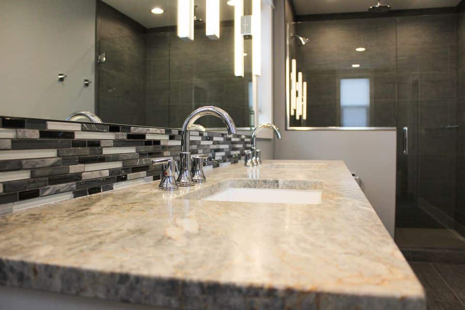 Bathroom vanity with dual sinks, granite countertop, and contemporary tile backsplash.