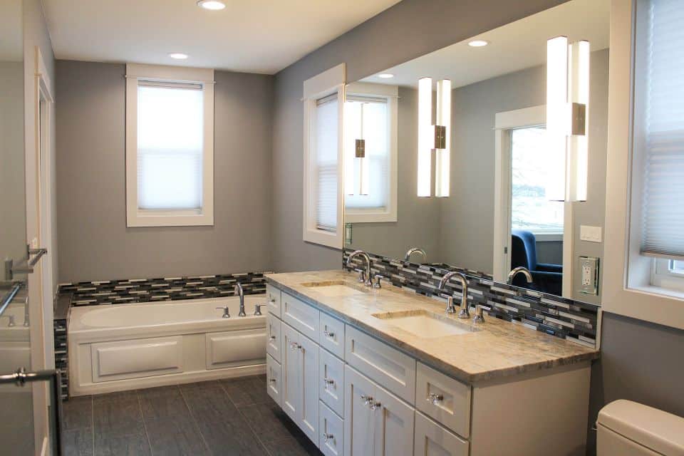 Modern bathroom with double vanity and bathtub.