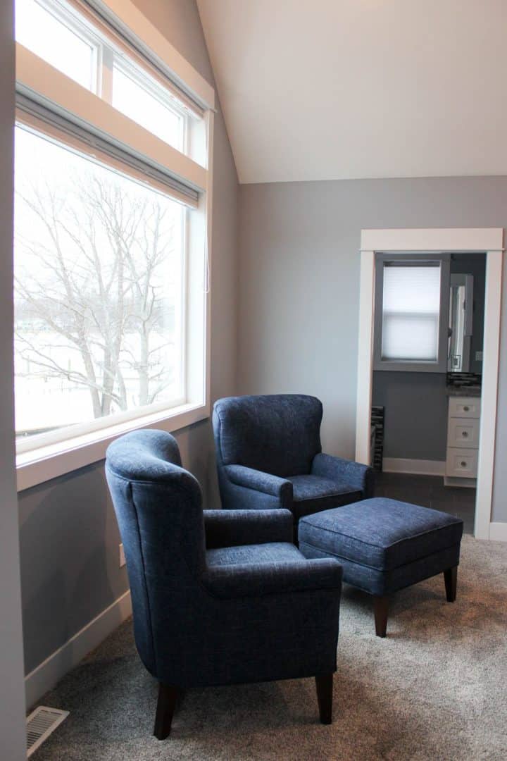 Comfortable blue armchairs in a bright corner reading nook with large window.