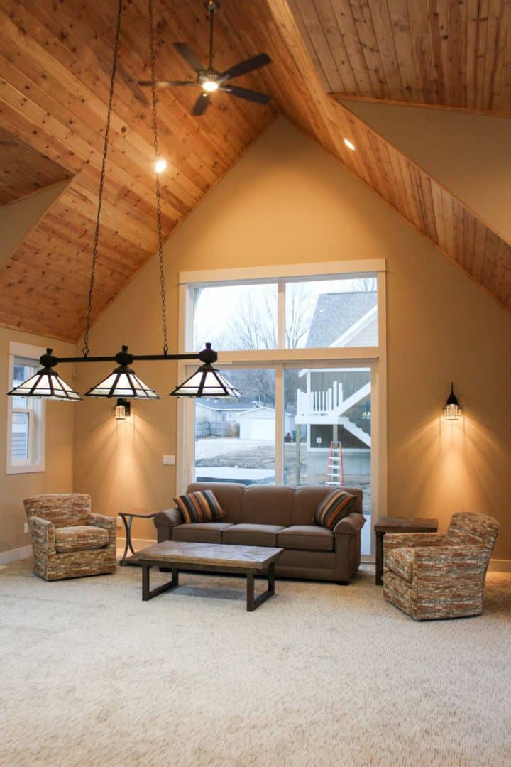 Bright living room with vaulted wooden ceiling, large window, and comfortable seating area.