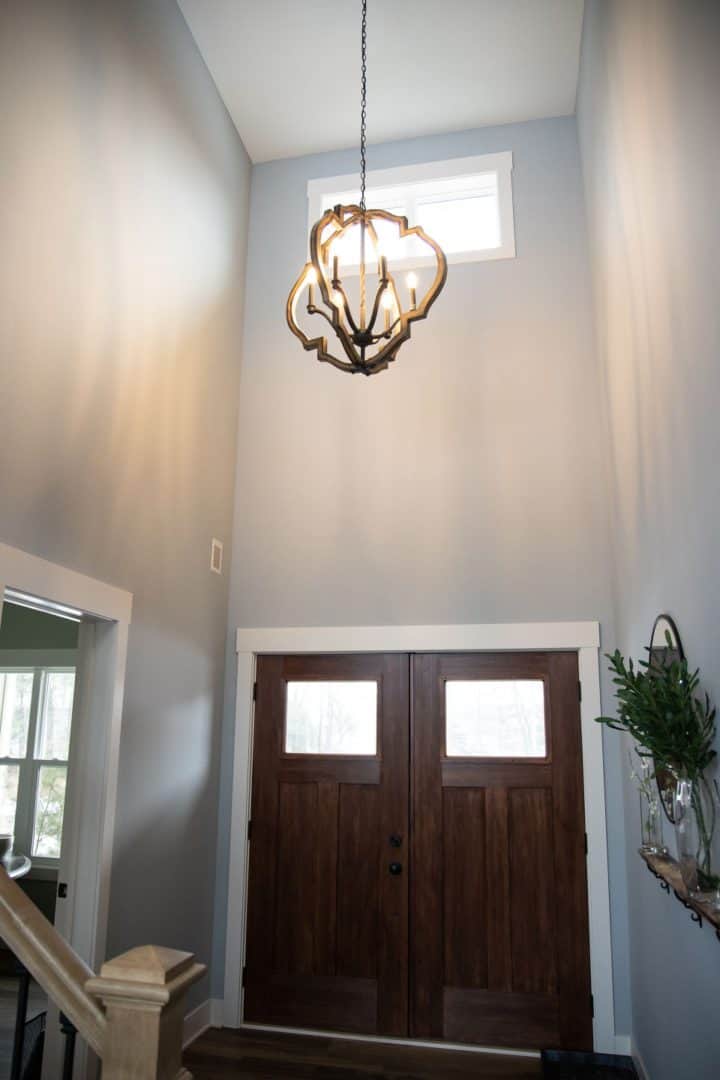 Stylish entryway with high ceilings, modern chandelier, and wooden double doors in a contemporary ho.