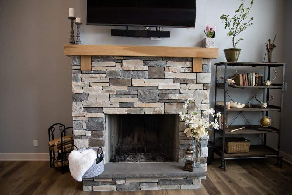Cozy stone fireplace with wooden mantel in a modern living room.
