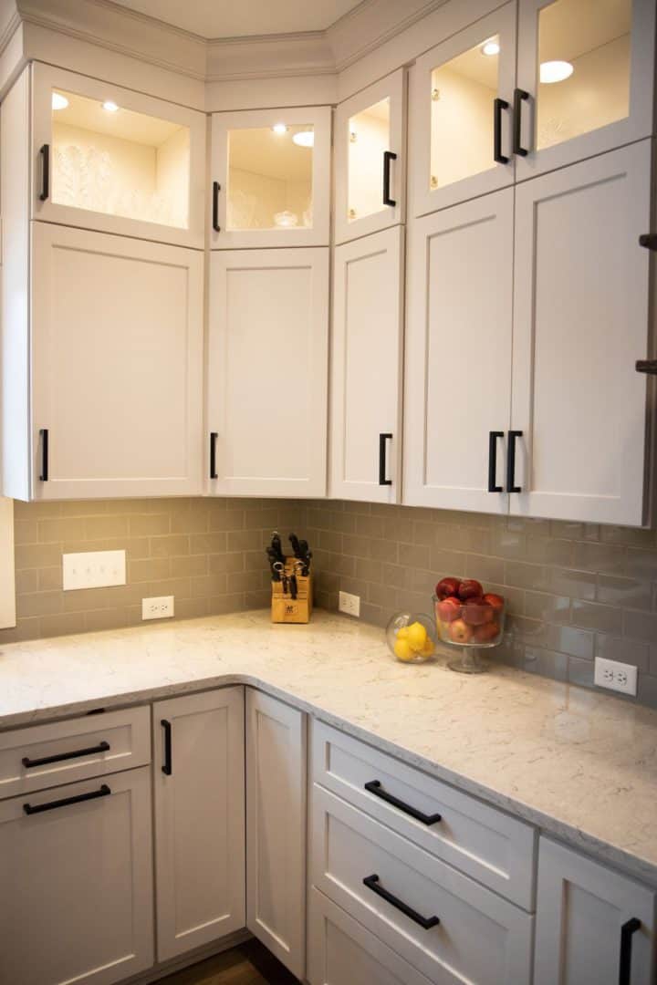 White kitchen cabinets with black hardware and a marble countertop for a sleek, contemporary look.