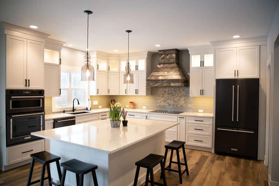 Bright modern kitchen with white cabinets, island, and stainless steel appliances.