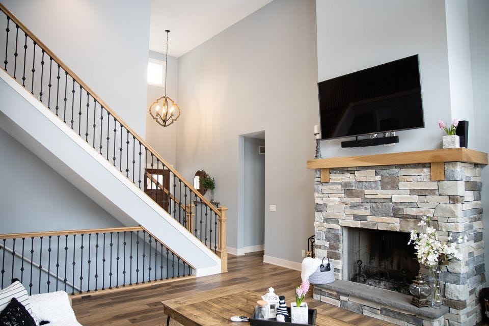 Spacious living room with modern decor, stone fireplace, and high ceilings by Livingston Homes.