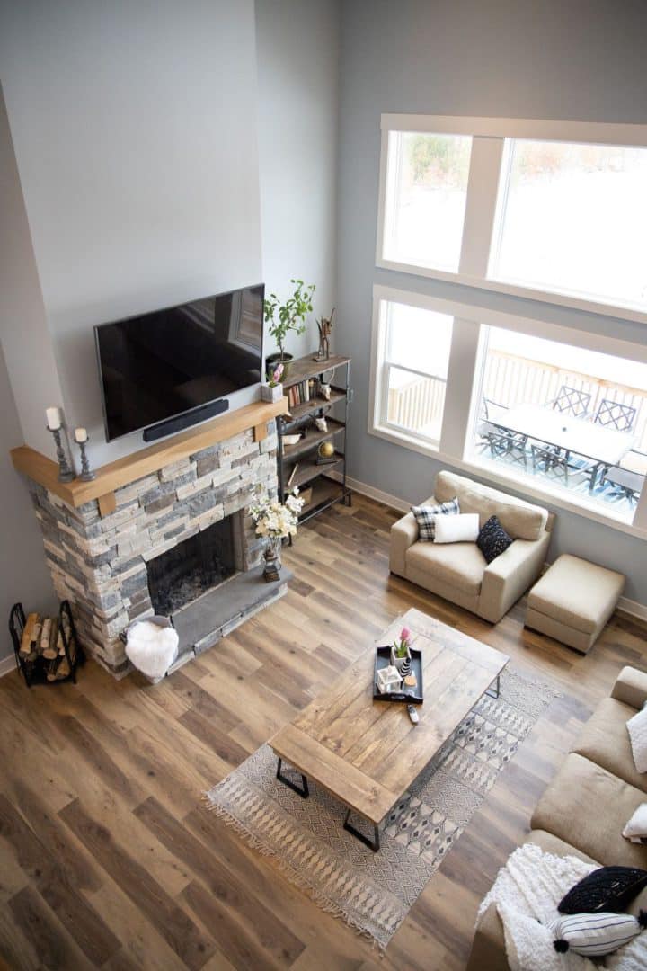 Living room with large windows, cozy sofas, and a stone fireplace for a warm, inviting atmosphere.