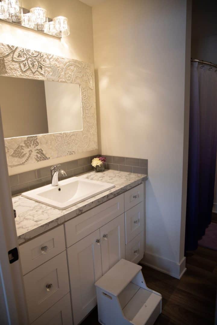 Bathroom vanity with marble countertop, elegant mirror, and soft lighting.